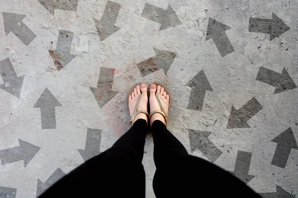 Many Direction Arrow Choices. Gold Shoes Isolated on Concrete Floor,Top View. Woman Standing is Feet Wearing Flip Flop (Sandal) on The Cement Floor Background Great For Any Use.