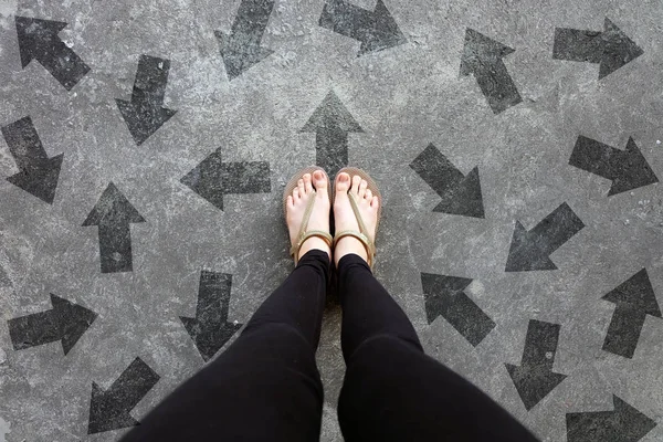 Many Direction Arrow Choices. Gold Shoes Isolated on Concrete Floor,Top View. Woman Standing is Feet Wearing Flip Flop (Sandal) on The Cement Floor Background Great For Any Use.