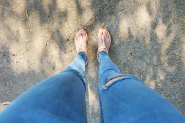 Çıplak ayakkabı kadın ve sarı ananas gömlek aksesuarları. Şehir arka planda sokak yolda çıplak sandalet ve eksikliği kot giyen kızın ayakları üzerinde kapat