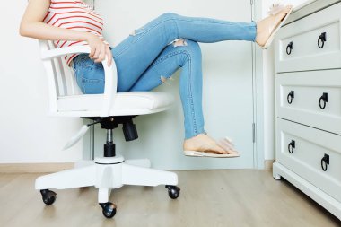 Portre insanlar oturup. Kadın moda çizgili turuncu gömlek ve-sizlik çekmek-Mavi Jeans. Arka plan beyaz sandalyede evde oturan güzel kadın