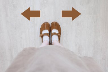 Kahverengi çizme farklı kahverengi karar ok ile en iyi görünümü. Bir çift ayak ayakta. Ayakkabı yön ahşap zemin arka plan üzerinde yürüyüş