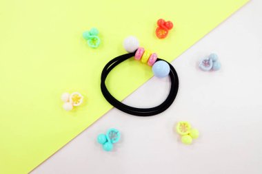 Boncuk moda aksesuarları ile siyah lastik bant. Saç elastik bant ile özgür yer. Siyah saç bandı ile pembe ve Sarı zemin üzerine izole renkli saç tokası