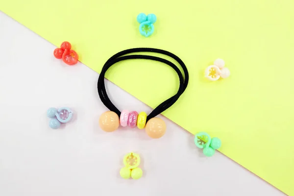 Black Rubber Band with Bead Fashion Accessories. Hair Elastic Band with Free Space. Black Hair Band with Colorful Hair Clip Isolated on Pink and Yellow Background