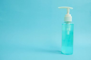 Coronavirus salgını ve COVID-19 önleme tıbbi alkol jeli şişesi mavi arka planda el virüsü koruması için. El hijyeni için dezenfektan şişesi yayılmış koruma sağlar. Sağlık hizmetleri kavramı.