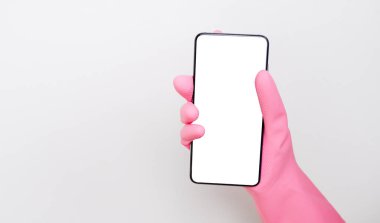 Coronavirus salgını ve COVID-19. Beyaz arkaplanda kırpma yolu ile izole edilmiş boş ekran ile el ele tutuşan telefon. Pembe lastik koruyucu eldivenler ve boş siyah akıllı telefon ekranı takan bir kadın..