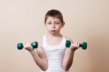 Yorgun, Fore, dumbbell ile küçük çocuk üzgün. Yüz ifadesi, spor