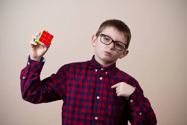 Уверенный в себе улыбающийся маленький мальчик-ботаник, держащий в руках кубик головоломки  . — стоковое фото