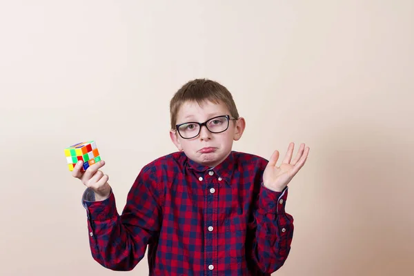 Запутавшийся маленький мальчик-ботаник, держащий кубик головоломки и руку на привет — стоковое фото