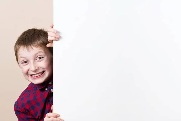 Счастливый улыбающийся мальчик, показывающий белый пустой плакат, доску — стоковое фото