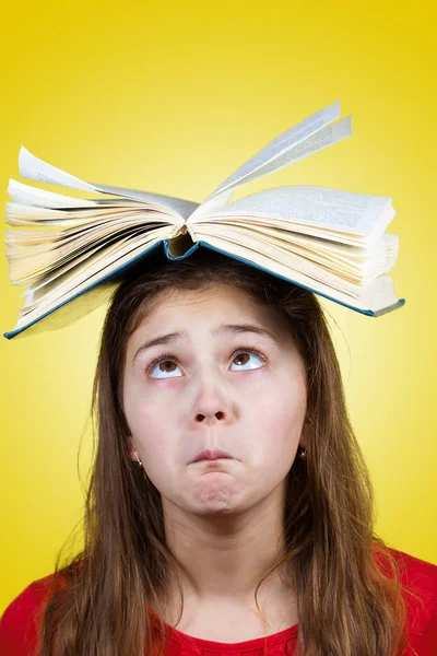Запутавшаяся маленькая школьница с открытой книгой на голове — стоковое фото