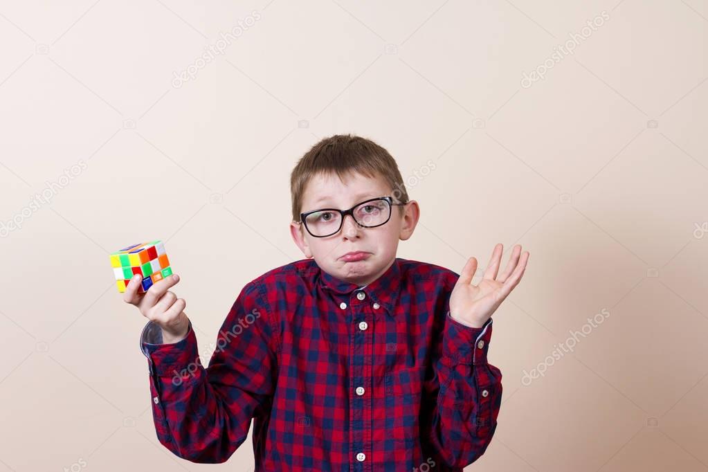 Confused little boy nerd ,holding a puzzle cube and a hand on hi