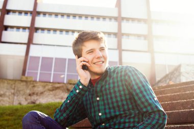 Kitap ve hareket eden telefon içinde konuşan gülümseyen genç adam bir