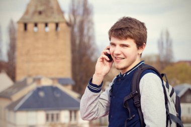 Genç adam bir şehirde cep telefonu konuşurken gülümseyen .