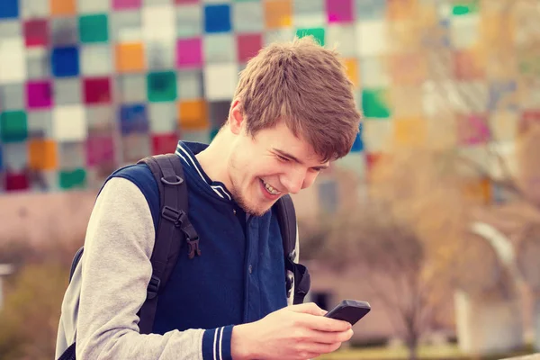 Un jeune homme souriant parle sur un téléphone portable dans une ville. — Photo