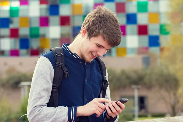 Un jeune homme souriant parle sur un téléphone portable dans une ville  . — Photo