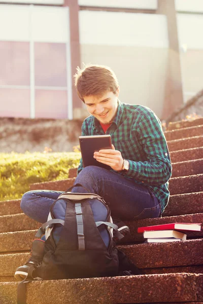 Smiling young man taping on tablet in a city on stair