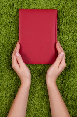 Kadının açık eller üzerinde yeşil arka plan izole bir kitap bir koruma jest yapma.