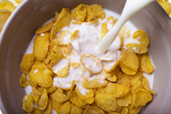 milk pouring into a bowl of  delicious corn flake cereals