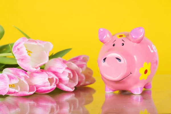 Piggy coin bank on yellow background with flowers