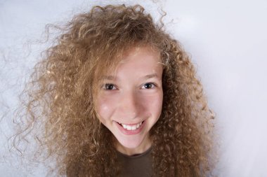 Kıvırcık saçlı küçük kız beyaz arka plan üzerinde gülümseyen mutlu. Mutluluk, çocukluk.