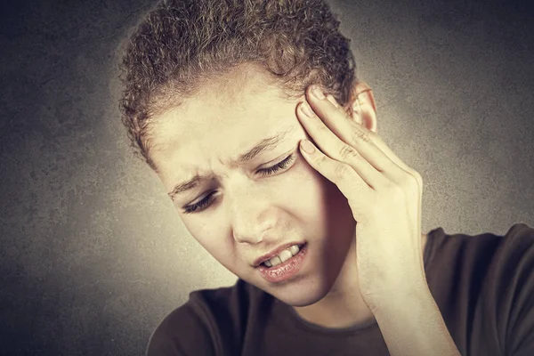 Portrait of little girl suffering from headache and holding hands on her head