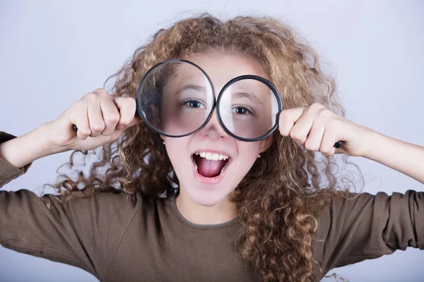 Funny portrait of cute little girl looking through  magnifying glass. — Stock Photo, Image