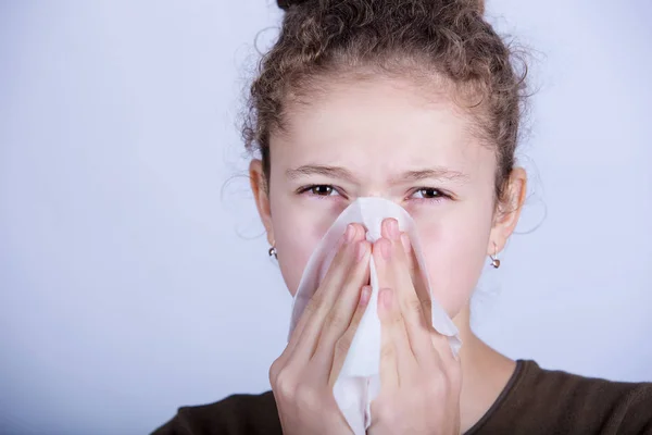 Little girl blows her nose with a napkin, isolated over white.