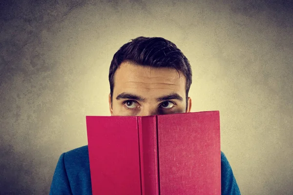 Pensando jovem estudante olhando para trás de um livro — Fotografia de Stock