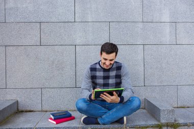 Kampüs içinde tablet taping gülümseyen genç adam 