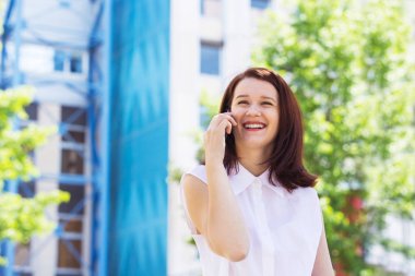 Hareket eden telefon kampüs içinde güneşli bir günde konuşan genç adam gülümseyen