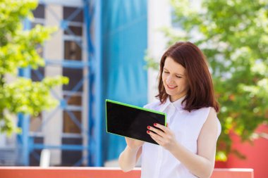 Tablet tablet kampüs Üniversitesi'nde kullanma taping gülümseyen genç kadın öğrenci.