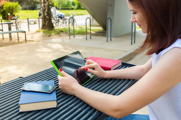 Jeune étudiante tapant sur tablette dans une ville sur banc d'université  . — Photo