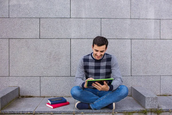 Усміхнений молодий чоловік знімається на планшеті в кампусі — стокове фото