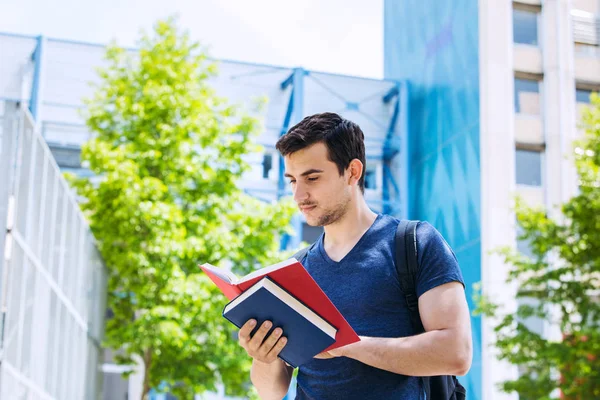 University.Smiling 若い学生男を保持、キャンパスの本を読んで — ストック写真