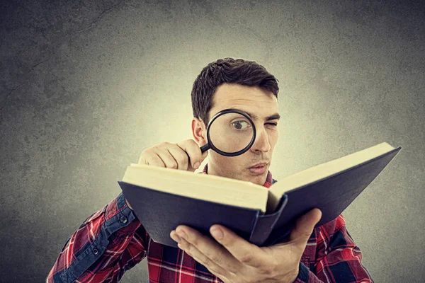 Kitap bir büyüteç ile meraklı genç öğrenci adam.