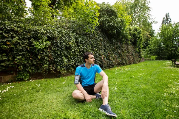 Fiatal férfi sportoló, pihenő, pihentető feküdt a füvön után futás és gyakorlati képzésre — Stock Fotó