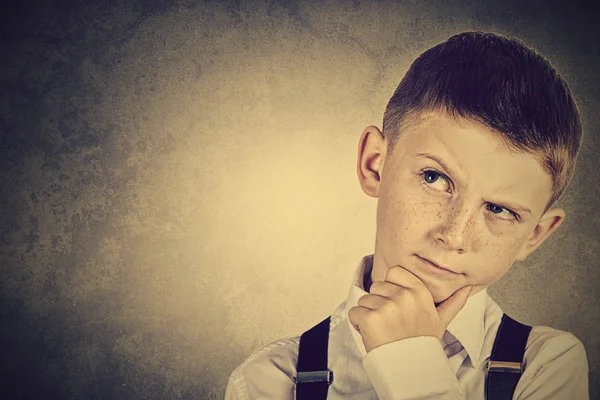 Портрет маленького мальчика, глубоко думающего о чем-то с рукой на подбородке — стоковое фото