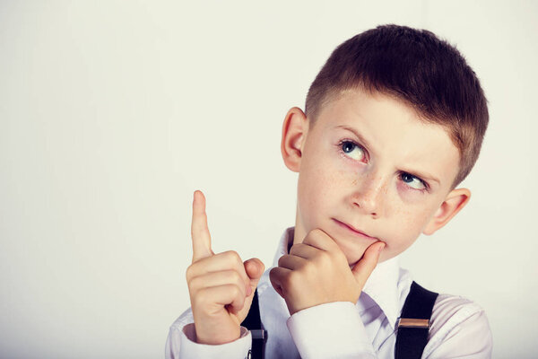 Думая о детском портрете маленького мальчика, который мыслит глубоко и указывает вверх
 