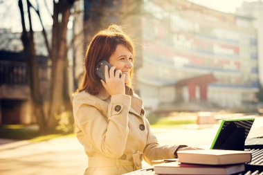 Cep telefonu kampüs Üniversitesi'nde tablet kullanarak konuşurken gülümseyen genç kadın öğrenci