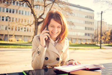 Cep telefonu kampüs Üniversitesi'nde tablet kullanarak konuşurken gülümseyen genç kadın öğrenci