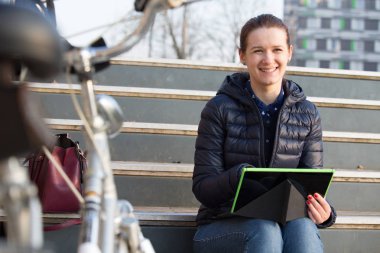 Tablet ve bisiklet ile açık havada genç gülümseyen öğrenci