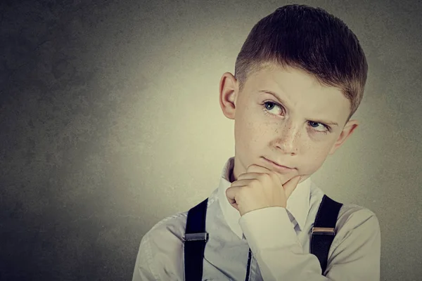 Et barneportrett av en liten gutt som tenker på noe med hånd på hake – stockfoto