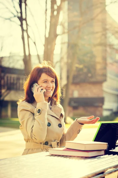 Sourire jeune étudiante parlant sur un téléphone portable en utilisant une tablette à l'université du campus — Photo