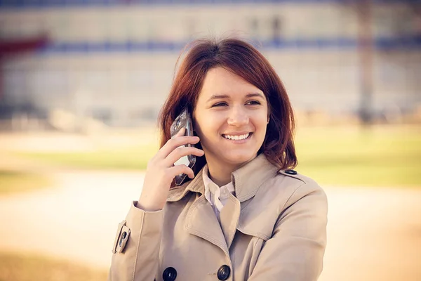 Smiling young woman student talking on mobile phone