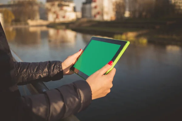 Woman, student holding using tablet in a city park near river
