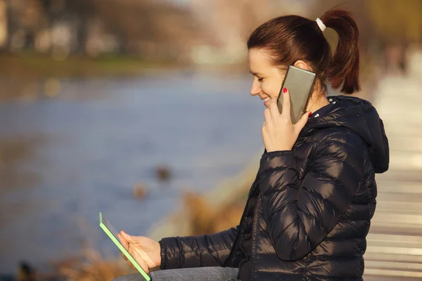 Jeune femme souriante, élève parlant à l'enregistrement téléphonique sur tablette en utilisant une tablette dans un parc de la ville — Photo