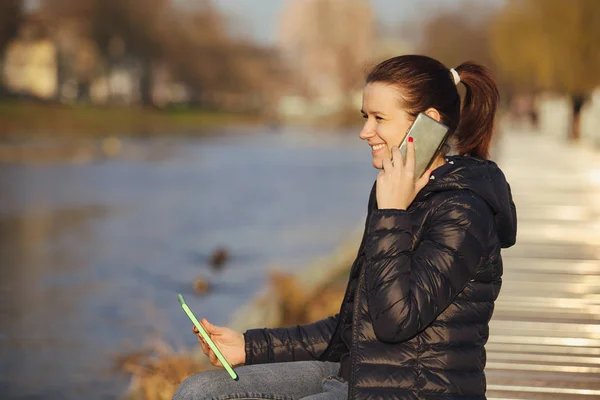 Jeune femme souriante, élève parlant à l'enregistrement téléphonique sur tablette à l'aide d'une tablette dans un parc urbain près de la rivière — Photo