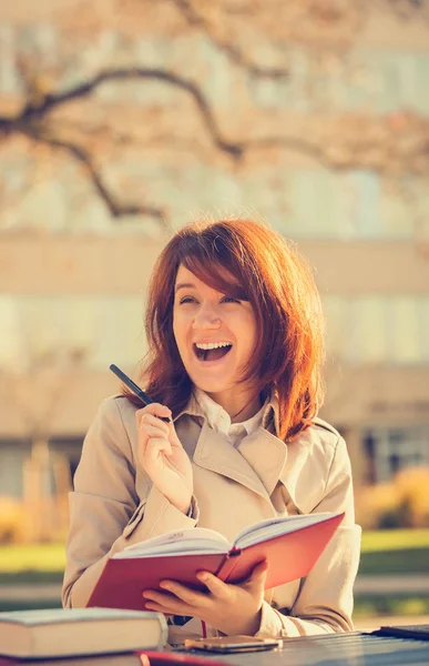 Happy student girl in campus holding a red journal