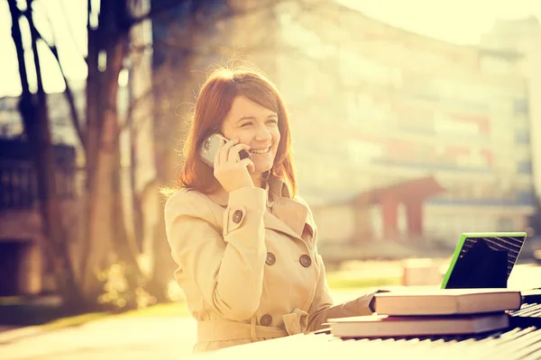 Sourire jeune étudiante parlant sur un téléphone portable en utilisant une tablette à l'université du campus . — Photo