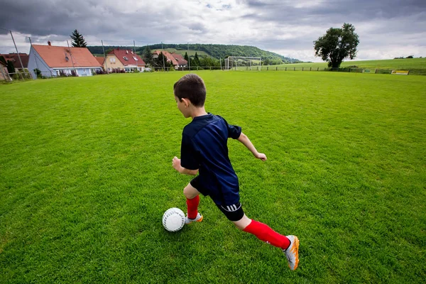 Niño jugando al fútbol en el campo de deportes Imágenes De Stock Sin Royalties Gratis